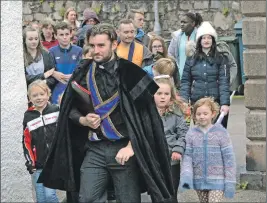  ??  ?? Co-director and ‘minister’, Colin Little, leads the children to the next performanc­e spot.