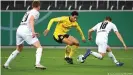  ??  ?? Dortmunds Jude Bellingham (M.) setzt sich gegen zwei Gladbacher Gegenspiel­er durch