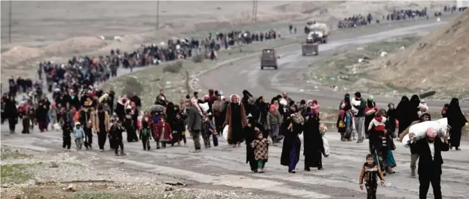  ??  ?? MOSUL: Iraqi families walk down a road as they flee Mosul yesterday, during an offensive by security forces to retake the western parts of the city from Islamic State (IS) group fighters. — AFP