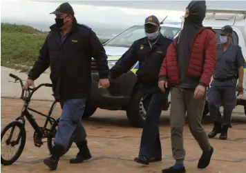  ?? African News Agency (ANA) ?? A SURFER is arrested at Muizenberg beach for breaking lockdown regulation­s. |