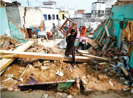  ?? AFP ?? An earthquake survivor moves his belongings in the rubble of collapsed houses on the outskirts of Mirpur in Pakistan-administer­ed Kashmir on Wednesday.
