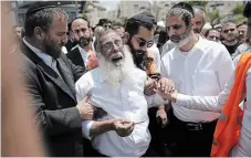  ?? ARIEL SCHALIT THE ASSOCIATED PRESS ?? Ultra-Orthodox Jewish mourners encircle a man overcome with grief at the funeral for Yonatan Havakuk and Boaz Gol, a day after they were killed in a stabbing attack in Elad, Israel, on Friday.