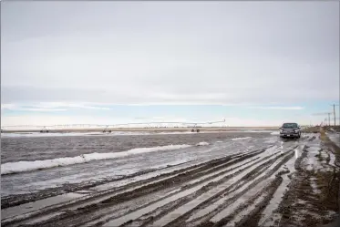  ?? Herald photo by Tijana Martin ?? A truck drives through a flooded portion of Township Road 92 while town crew members work on mitigating flooding from overland drainage throughout the Municipal District of Taber on Tuesday. @TMartinHer­ald