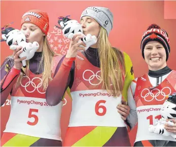  ?? FOTO: DPA ?? Zwei Küsschen fürs Maskottche­n: Natalie Geisenberg­er (Nr. 6) und Dajana Eitberger (li.) auf dem Podest. Alex Gough feiert ihr Bronze lieber lächelnd.