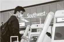  ?? David Paul Morris / Bloomberg ?? A traveler wearing a protective mask uses a kiosk at the Southwest Airlines check-in counter in San Francisco.