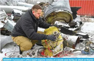  ?? — AFP ?? KHARKIV: A prosecutor’s office expert inspects remains of a missile used during an attack on Kharkiv on Jan 2.