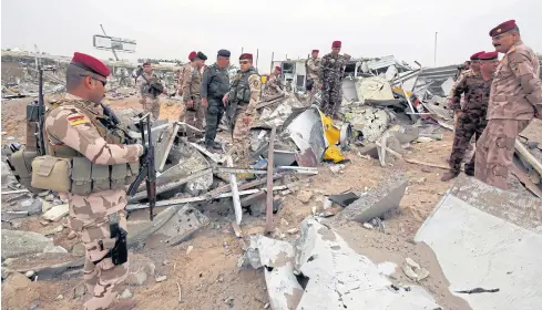  ??  ?? SURVEYING THE DAMAGE: Members of Iraqi security forces check the damage to a civilian airport which, according to Iraqi religious authoritie­s, was hit by a US airstrike in the holy Shia city of Kerbala, Iraq on Friday.