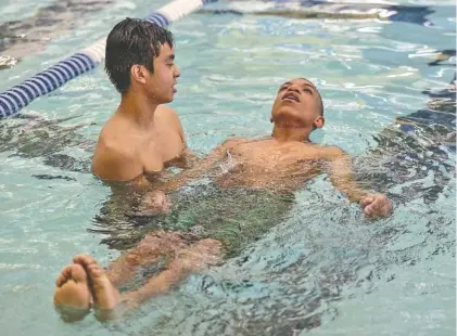  ?? STAFF PHOTOS BY DOUG STRICKLAND ?? Charles Hoang, left, helps Rickey Maples learn to float on his back during a swim period at McCallie School’s Bridge Scholars summer program on Wednesday. The program gives students in underserve­d communitie­s new learning experience­s.