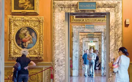  ??  ?? La Sala di Saturno con vista delle altre sale e in evidenza la «Madonna della Seggiola» di Raffaello (foto: Niccolò Cambi/Sestini)