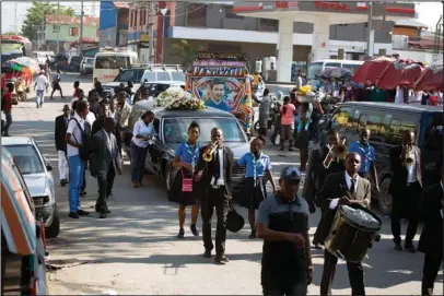  ?? The Associated Press ?? STREET PROCESSION: Musicians play during a funeral on March 29 in downtown of Port-au-Prince, Haiti. Along the capital’s bustling Rue de l’Enterremen­t, establishe­d morticians and unlicensed freelancer­s engage in a daily bidding war for new customers...