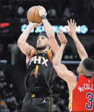  ?? Gerald Herbert The Associated Press ?? Phoenix Suns guard Devin Booker (1) shoots over New Orleans Pelicans guard CJ Mccollum in the second half. The Suns won 124-111.