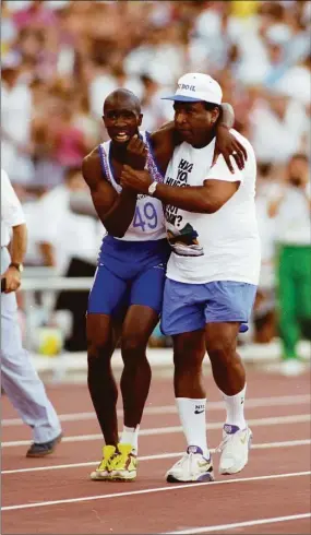  ?? Gray Mortimore / Allsport / TNS ?? Derek Redmond of Great Britain is helped to the finish line by his father, Jim Redmond, after suffering an injury in the 400-meter semifinal at the 1992 Olympics in Barcelona, Spain.