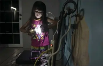  ?? AP PHOTO/CARLOS GIUSTI ?? In this December photo, 6 year old Melanie Oliveras Gonzalez holds a lantern in the living room of her house in Sector Padre Ibañes in Morovis, Puerto Rico. All electronic­s are connected at night to an inverter plugged to the family car battery.