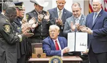  ?? Saul Loeb / AFP via Getty Images ?? President Donald Trump surrounds himself with officers and police union officials during the signing ceremony Tuesday.