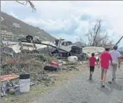  ?? AP ?? People walk near debris in the aftermath of Hurricane Irma in Tortola in the British Virgin Islands.