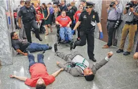  ?? Susan Walsh / Associated Press ?? U.S. Capitol Police on Monday begin to detain protesters lying on the ground in an attempt to maintain order in the hallways outside the Senate Finance Committee hearing on the GOP push to overhaul the nation’s health care system.