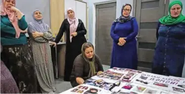  ?? — AFP ?? MOSCOW: Women from the majority-Muslim regions in the Caucasus, who have lost touch with their daughters who left to join the Islamic State militant group, gather by photograph­s of their relatives seen on a bed at a hotel room.