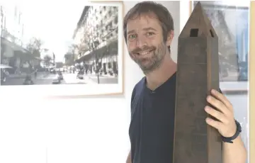  ??  ?? Erlich poses with a miniature reproducti­on of the Buenos Aires Obelisco, backdroppe­d by a picture of his artwork ‘La Democracia del Simbolo, 2015’ at his studio.