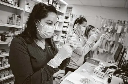  ?? David Zalubowski / Associated Press ?? Pharmacist Claudia Coronoa-Guevara, from left, joins registered nurses Amy Wells and Megan McLaughlin in drawing shots of Johnson & Johnson’s COVID vaccine Saturday in the pharmacy of National Jewish Hospital for distributi­on in east Denver.