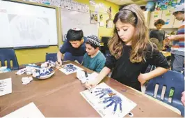  ?? PAUL SANCYA/AP ?? Second-grader Talia Begres, 7, works on creating a menurkey, a paper-and-paint mashup of a menorah and turkey, at Hillel Day School in Farmington Hills, Mich.