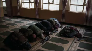  ?? (AP/Felipe Dana) ?? Taliban members lay their weapons down Sunday as they pray inside a mosque in Kabul, Afghanista­n.