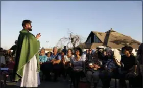  ?? DAVID GOLDMAN — THE ASSOCIATED PRESS ?? Father Michael Nixon holds Mass outside Saint Dominic Catholic Church, which stands damaged in the background from hurricane Michael in Panama City, Fla., on Saturday.