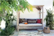  ??  ?? n At left, Betsy Burnham shows a rustic daybed on a patio in Los Angeles. As basic patio decorating has grown into the idea of creating an “outdoor living room,” seating options have come to include items like this.