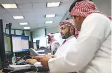  ?? Bloomberg ?? Employees at the Alawwal Bank monitor financial data displayed on the bank’s trading floor in Riyadh.