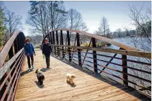  ?? AJC FILE PHOTO ?? Linda Cahn (left) walks her dog, Po, alongside Vicki Robertson and her dog, Charlie, at Murphey Candler Park in Brookhaven in 2014. The park will gain a new building, trail and boardwalk.
