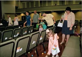  ??  ?? Lennon Hammond, center, 4, scoops up Easter eggs as her mother, Ashleigh Hammond, looks on during the “Eggstravag­anza,” which was moved inside due to stormy weather.