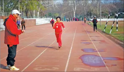  ?? ZHAO XINGWU / FOR CHINA DAILY ?? Chen Xuhua trains with her husband, Li Zhipo, at a running track in Jinan, Shandong province.