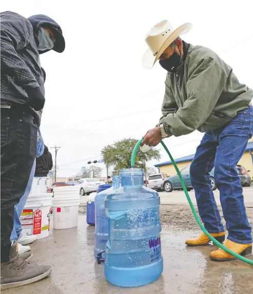  ?? DAVID J. PHILLIP / THE ASSOCIATED PRESS ?? Leovardo Perez, right, fills a water jug using a hose from a public park water spigot Thursday in Houston. Officials have ordered seven million Texans to boil tap water before drinking it following days of record low temperatur­es.