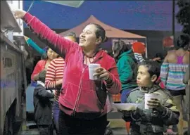  ??  ?? A WOMAN accepts food served by the Mexican Marines outside Benito Juarez Sports Center, which is functionin­g as a migrant shelter, on Monday in Tijuana.