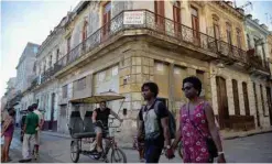  ?? — AFP ?? People walk past a building with a ‘For sale’ sign in Havana, Cuba.