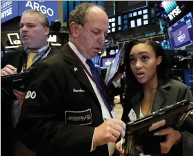  ?? AP/RICHARD DREW ?? (center), confers Monday with colleague Lauren Simmons on the floor of the New York Stock Exchange. Trader Gordon Charlop