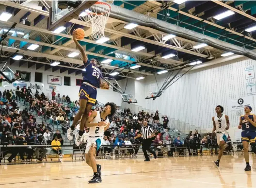  ?? STAFF FILE ?? Menchville returnee Jordan Watlington (23) last season dunks over Woodside player Trevor Smith (2), who now plays for the Richmond Spiders.