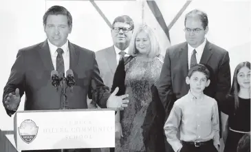  ?? CARL JUSTE cjuste@miamiheral­d.com ?? Florida Gov. Ron DeSantis, left, names a second judge from Miami's appeals court, Judge Robert Luck, at right, to the state Supreme Court on Monday. Luck stands with his parents, Joey and Susie Luck and his children Jacob and Julia at Scheck Hillel Community School in Northeast Miami Dade.