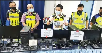  ??  ?? Ahsmon (third left), his deputy Supt Merbin Lisa (second left) and other police personnel show the computers seized during the raid.