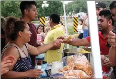  ??  ?? Alejandra Morales serves elote to a hungry customer during the Third of July Celebratio­n. Morales and her family were preparing a variety of flavorful cultural dishes for attendees.