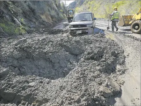  ?? Reed Saxon Associated Press ?? CREWS WORK to free a car trapped by a mudslide that closed Topanga Canyon Boulevard on Thursday in the Santa Monica Mountains.