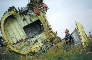  ?? – Reuters File ?? ILL-FATED FLIGHT: A Malaysian air crash investigat­or inspects the crash site of Malaysia Airlines Flight MH17, near the village of Hrabove in Donetsk region, Ukraine, on July 22, 2014.