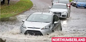  ??  ?? Making waves: Traffic waits to plough through the flooded street in Whitley Bay