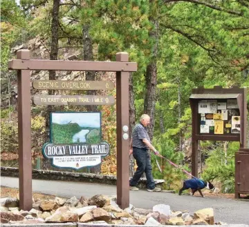  ??  ?? A hiker walks his dog along one of Pinnacle Mountain State Park’s marked trails.