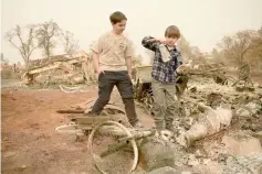  ??  ?? Jeremie (left) and Jacob Saylors look at religious statues they found in the burned remains of their home in Paradise. — AFP photo