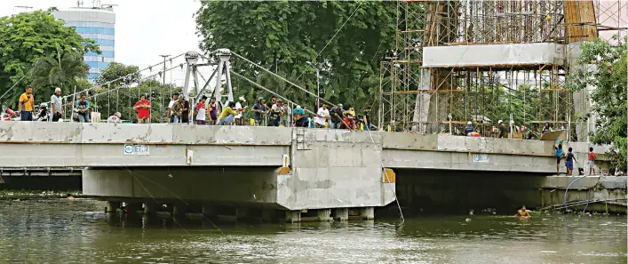  ?? DIPTA WAHYU JAWA POS ?? COBA PERUNTUNGA­N: Puluhan warga memancing ikan ’’mabuk’’ di Jembatan Joyoboyo yang sudah selesai konstruksi­nya. Sementara itu, warga lainnya memilih menjaring ikan di tepi Kalimas.