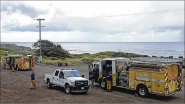  ?? MARCO GARCIA / AP ?? Honolulu Fire Department members gather at the entrance of Kaena Point on Wednesday in Waialua, Hawaii. An Army helicopter with five on board crashed several miles off Oahu’s North Shore late Tuesday.
