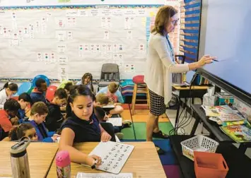  ?? TAMPA BAY TIMES PHOTOS ?? Second-grade teacher Barbara Zimmer writes letters on a screen while her students listen and write on their marker boards at Bay Crest Elementary School in Town ’N Country.