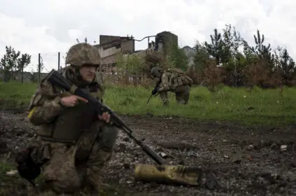  ?? Mstyslav Chernov, The Associated Press ?? Ukrainian servicemen squat during a patrol in a recently retaken village north of Kharkiv, east Ukraine, on Sunday. Finland and Sweden are looking to join NATO amid Russia’s invasion of Ukraine.