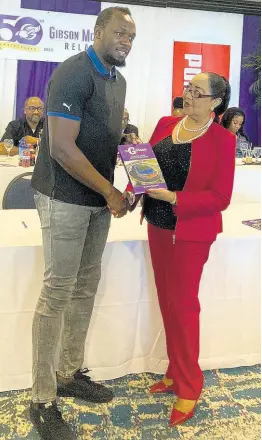  ?? SHARLA WILLIAMS ?? Patron of the Gibson Mccook Relays Usain Bolt (left) receives book depicting 40 years of the event’s history from Dr Marion Bullock Ducasse, vice-chairman of the Gibson Mccook Relays organising committee, during a sponsors’ luncheon for its 50th anniversar­y at The Jamaica Pegasus hotel in New Kingston yesterday.