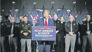 ?? PAUL SANCYA/THE ASSOCIATED PRESS ?? Republican presidenti­al candidate former President Donald Trump, flanked by law enforcemen­t officers, speaks at a campaign event in Grand Rapids, Mich., on Tuesday. “Under Crooked Joe Biden, every state is now a border state. Every town is now a border town,” Trump said.